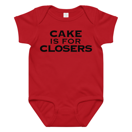 "Cake Is For Closers" printed on a red baby jersey bodysuit laying on a flat surface amongst other clothes