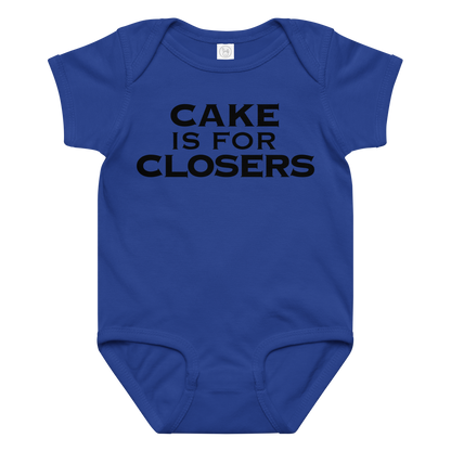 "Cake Is For Closers" printed on a royal baby jersey bodysuit laying on a flat surface amongst other clothes