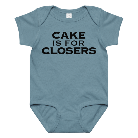 "Cake Is For Closers" printed on a vintage indigo baby jersey bodysuit laying on a flat surface amongst other clothes