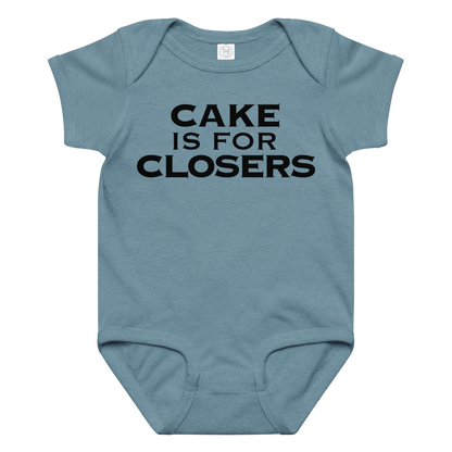 "Cake Is For Closers" printed on a vintage indigo baby jersey bodysuit laying on a flat surface amongst other clothes