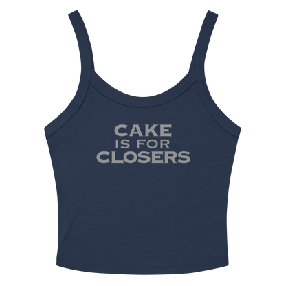 "Cake Is For Closers" printed on a solid navy blend women's micro-rib tanktop laying on a flat surface amongst sunglasses and shorts