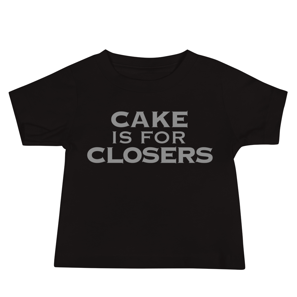 "Cake Is For Closers" printed on a black baby jersey short sleeve tee laying on a flat surface