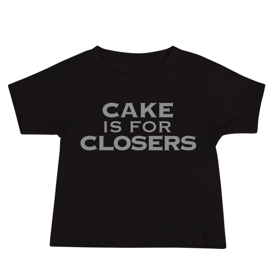 "Cake Is For Closers" printed on a black baby jersey short sleeve tee laying on a flat surface