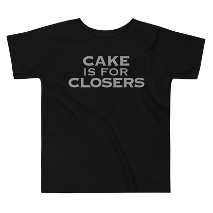 "Cake Is For Closers" printed on a black toddler short sleeve tee laying on a flat surface