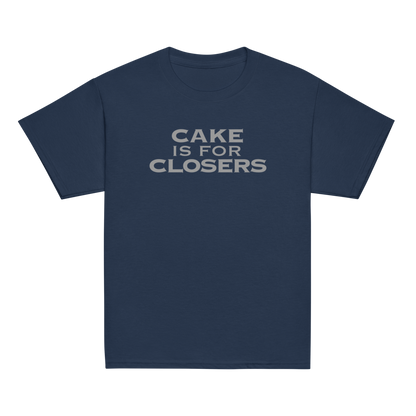"Cake Is For Closers" printed on a navy youth classic tee laying on a flat surface