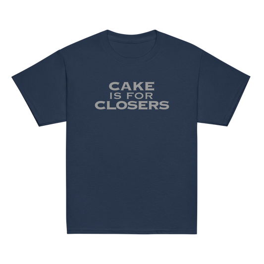"Cake Is For Closers" printed on a navy youth classic tee laying on a flat surface