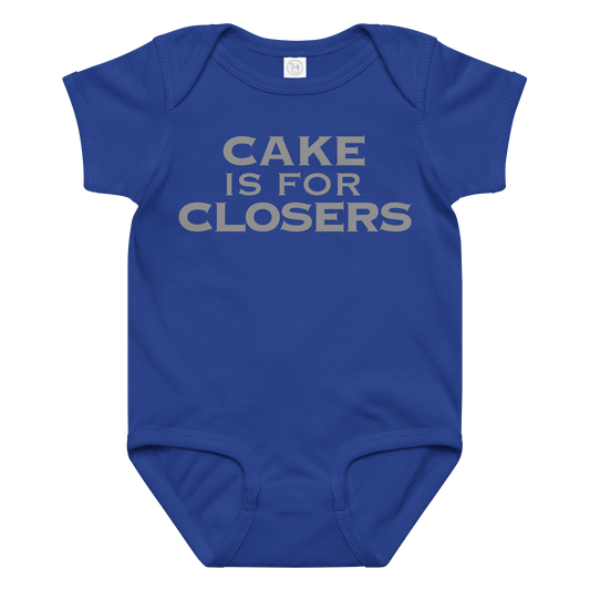 "Cake Is For Closers" printed on a royal baby jersey bodysuit laying on a flat surface amongst other clothes