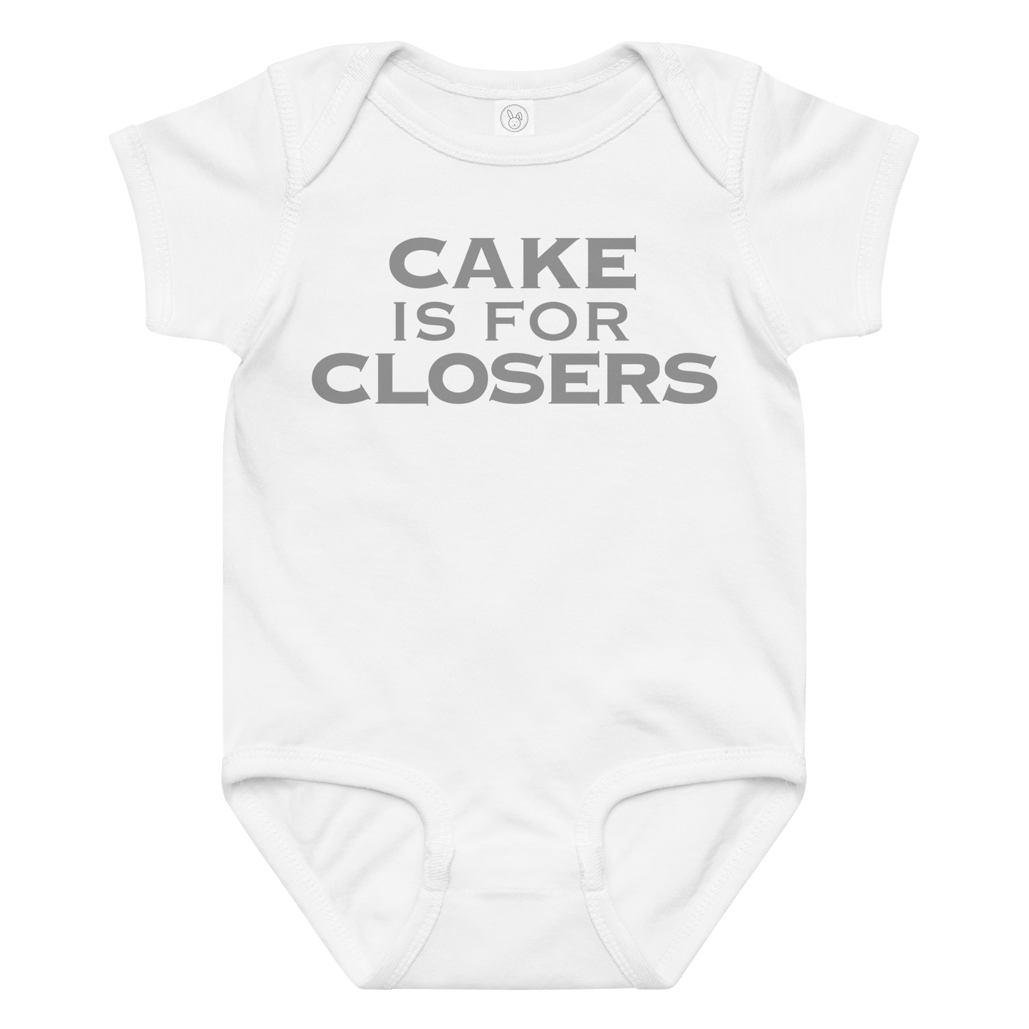 "Cake Is For Closers" printed on a white baby jersey bodysuit laying on a flat surface amongst other clothes
