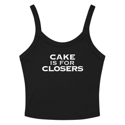 "Cake Is For Closers" printed on a solid black blend women's micro-rib tanktop laying on a flat surface amongst sunglasses and shorts