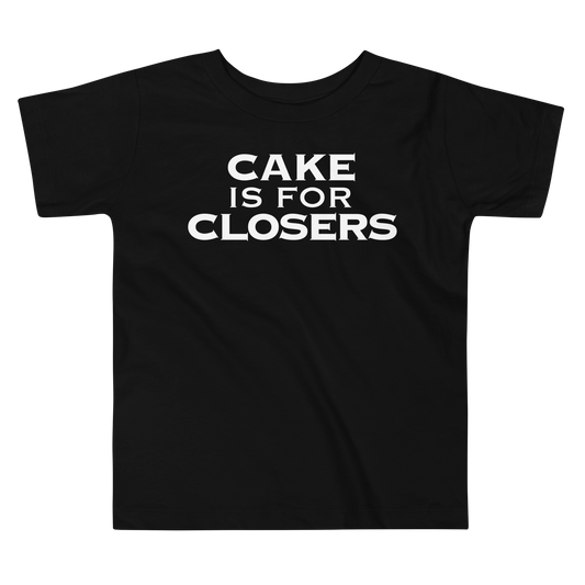 "Cake Is For Closers" printed on a black toddler short sleeve tee laying on a flat surface
