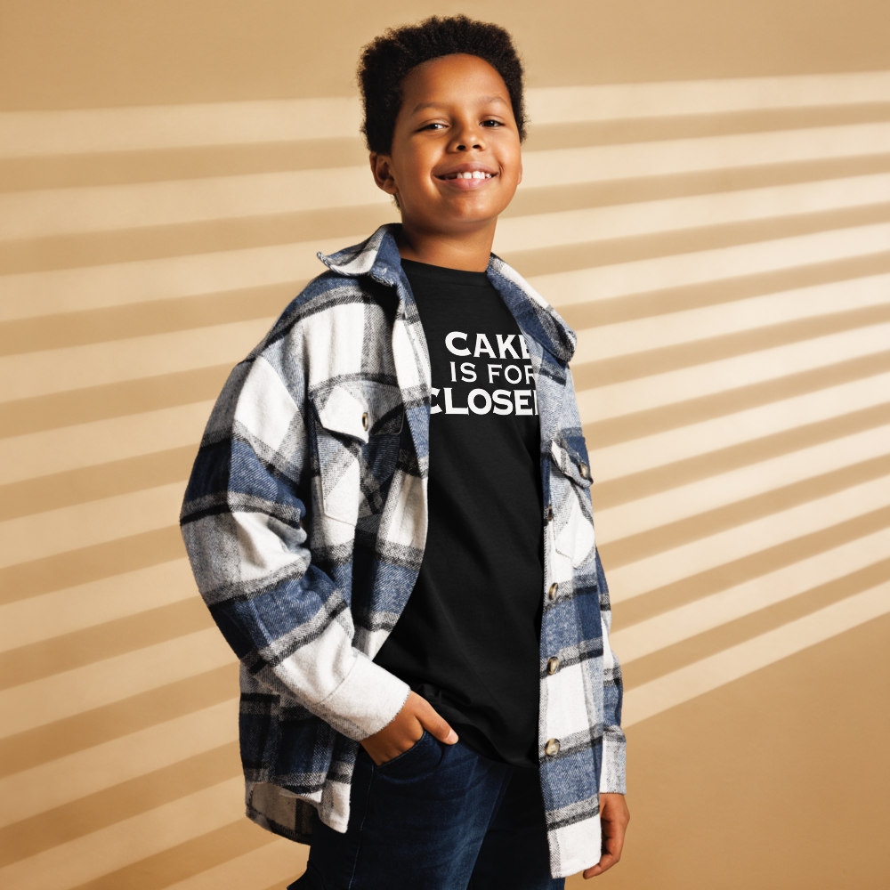 "Cake Is For Closers" printed on a black youth classic tee worn by a male also wearing a jacket