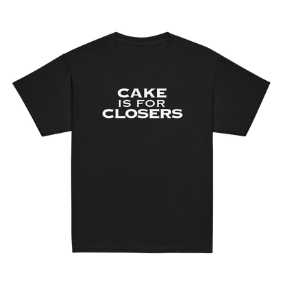"Cake Is For Closers" printed on a black youth classic tee laying on a flat surface