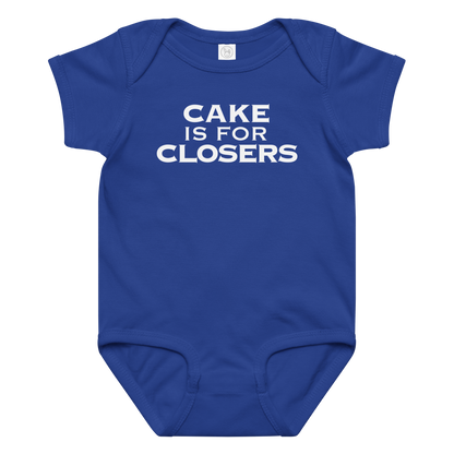"Cake Is For Closers" printed on a royal baby jersey bodysuit laying on a flat surface amongst other clothes