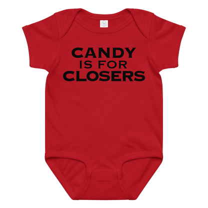 "Candy Is For Closers" printed on a red baby jersey bodysuit laying on a flat surface amongst other clothes