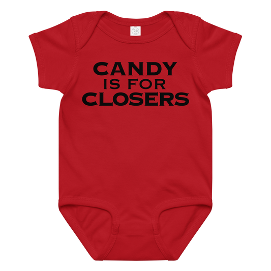 "Candy Is For Closers" printed on a red baby jersey bodysuit laying on a flat surface amongst other clothes