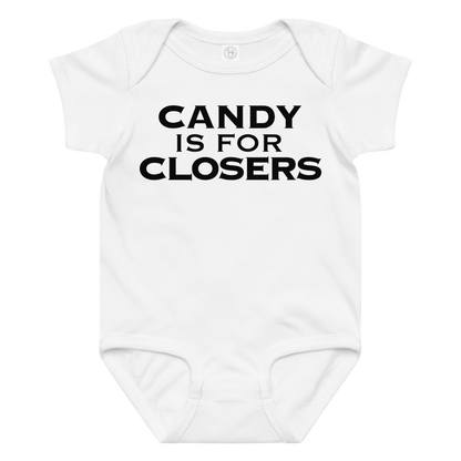 "Candy Is For Closers" printed on a white baby jersey bodysuit laying on a flat surface amongst other clothes