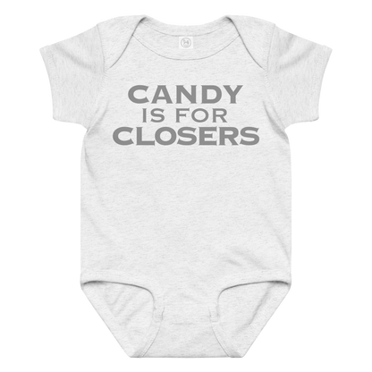"Candy Is For Closers" printed on a ash baby jersey bodysuit laying on a flat surface amongst other clothes