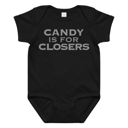 "Candy Is For Closers" printed on a black baby jersey bodysuit laying on a flat surface amongst other clothes