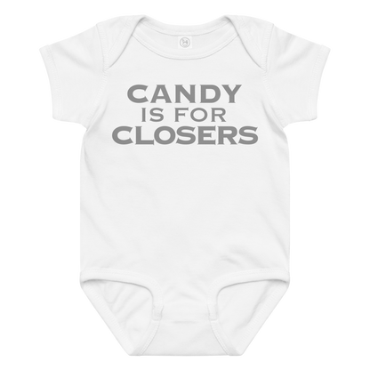 "Candy Is For Closers" printed on a white baby jersey bodysuit laying on a flat surface amongst other clothes