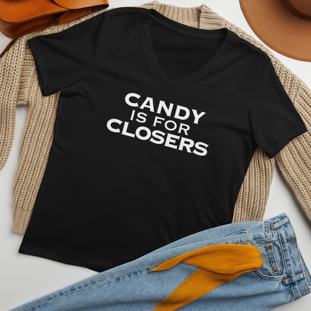 "Candy Is For Closers" printed on a solid black blend women's relaxed v-neck t-shirt laying on a flat surface amongst other clothes