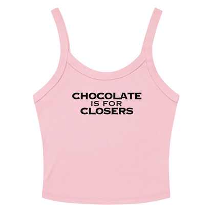 "Chocolate Is For Closers" printed on a solid pink blend women's micro-rib tanktop laying on a flat surface amongst sunglasses and shorts