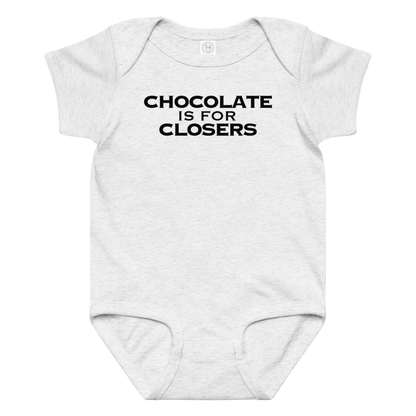 "Chocolate Is For Closers" printed on a ash baby jersey bodysuit laying on a flat surface amongst other clothes
