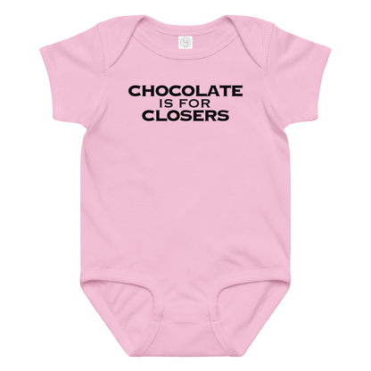 "Chocolate Is For Closers" printed on a pink baby jersey bodysuit laying on a flat surface amongst other clothes