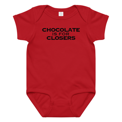 "Chocolate Is For Closers" printed on a red baby jersey bodysuit laying on a flat surface amongst other clothes