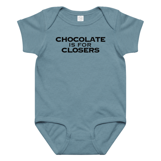 "Chocolate Is For Closers" printed on a vintage indigo baby jersey bodysuit laying on a flat surface amongst other clothes