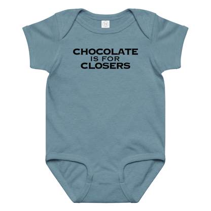 "Chocolate Is For Closers" printed on a vintage indigo baby jersey bodysuit laying on a flat surface amongst other clothes