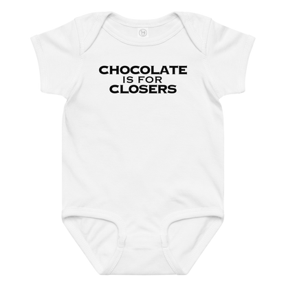"Chocolate Is For Closers" printed on a white baby jersey bodysuit laying on a flat surface amongst other clothes