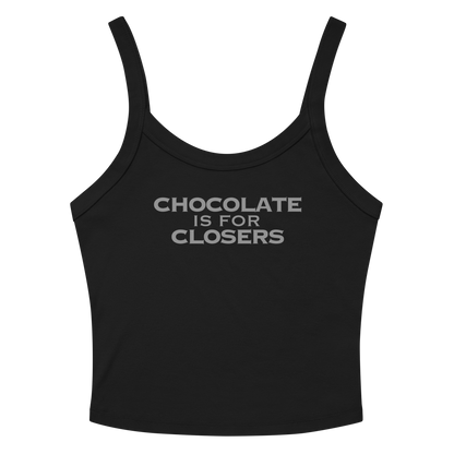 "Chocolate Is For Closers" printed on a solid black blend women's micro-rib tanktop laying on a flat surface amongst sunglasses and shorts
