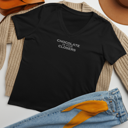 "Chocolate Is For Closers" printed on a solid black blend women's relaxed v-neck t-shirt laying on a flat surface amongst other clothes