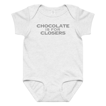 "Chocolate Is For Closers" printed on a ash baby jersey bodysuit laying on a flat surface amongst other clothes