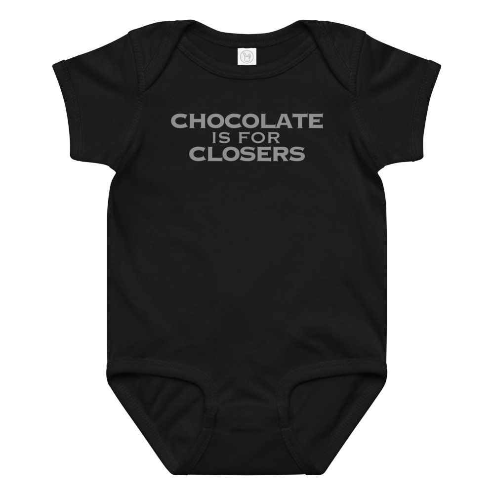 "Chocolate Is For Closers" printed on a black baby jersey bodysuit laying on a flat surface amongst other clothes