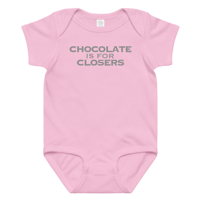 "Chocolate Is For Closers" printed on a pink baby jersey bodysuit laying on a flat surface amongst other clothes
