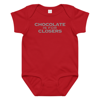 "Chocolate Is For Closers" printed on a red baby jersey bodysuit laying on a flat surface amongst other clothes