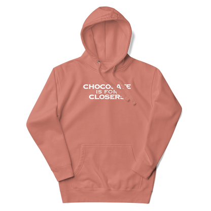 "Chocolate Is For Closers" printed on a dusty rose unisex hoodie laying on a flat surface with the hood up