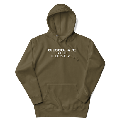 "Chocolate Is For Closers" printed on a military green unisex hoodie laying on a flat surface with the hood up