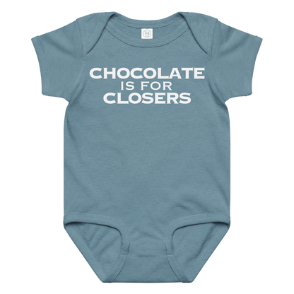 "Chocolate Is For Closers" printed on a vintage indigo baby jersey bodysuit laying on a flat surface amongst other clothes