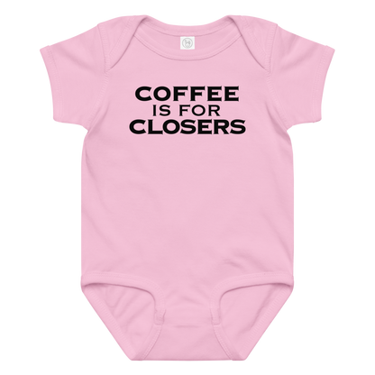 "Coffee Is For Closers" printed on a pink baby jersey bodysuit laying on a flat surface amongst other clothes