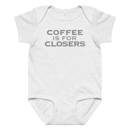 "Coffee Is For Closers" printed on a ash baby jersey bodysuit laying on a flat surface amongst other clothes
