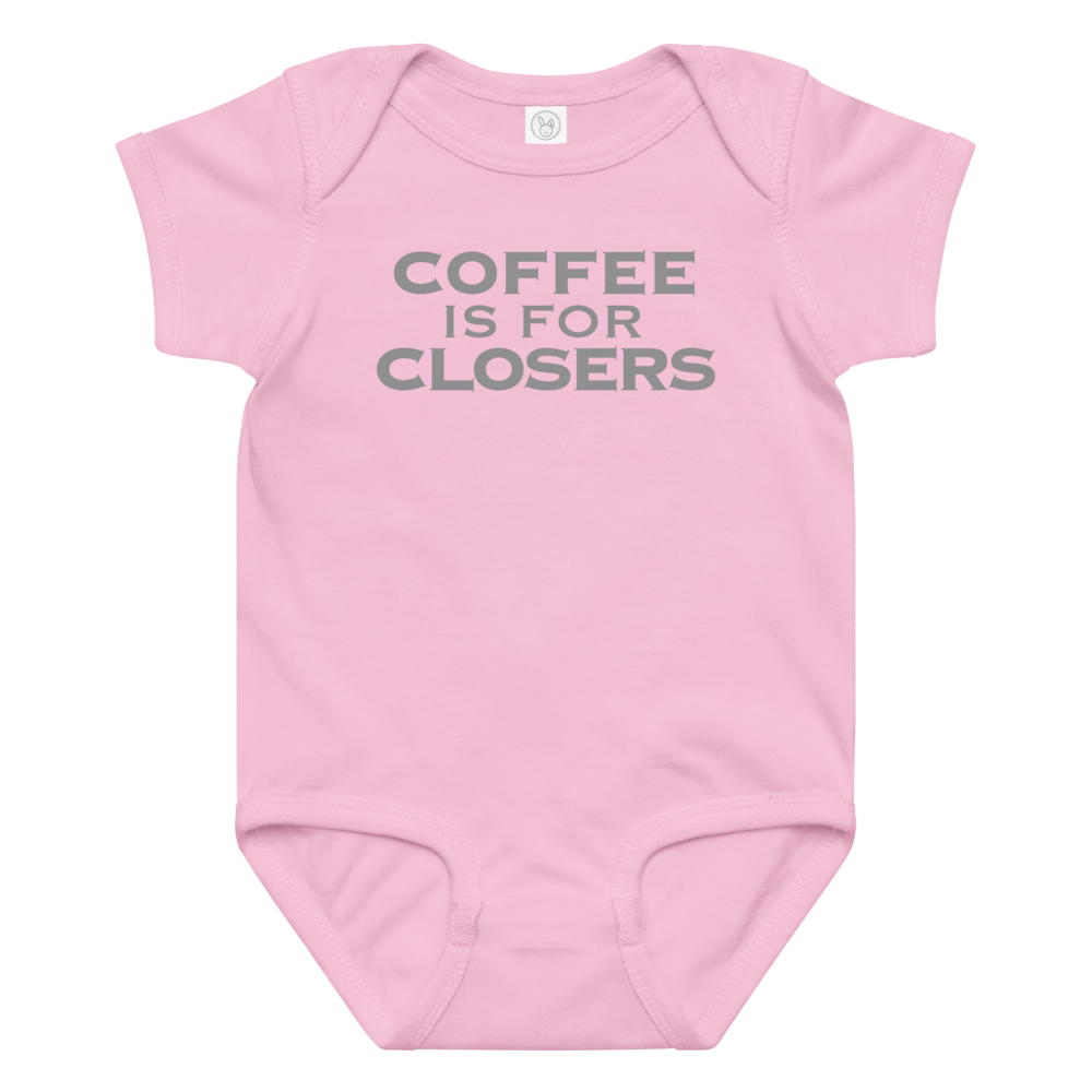 "Coffee Is For Closers" printed on a pink baby jersey bodysuit laying on a flat surface amongst other clothes