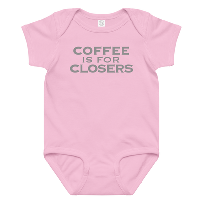 "Coffee Is For Closers" printed on a pink baby jersey bodysuit laying on a flat surface amongst other clothes
