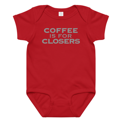 "Coffee Is For Closers" printed on a red baby jersey bodysuit laying on a flat surface amongst other clothes