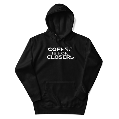 "Coffee Is For Closers" printed on a black unisex hoodie laying on a flat surface with the hood up