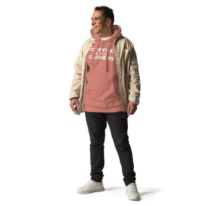 "Coffee Is For Closers" printed on a dusty rose unisex hoodie worn by a male with a jacket on top