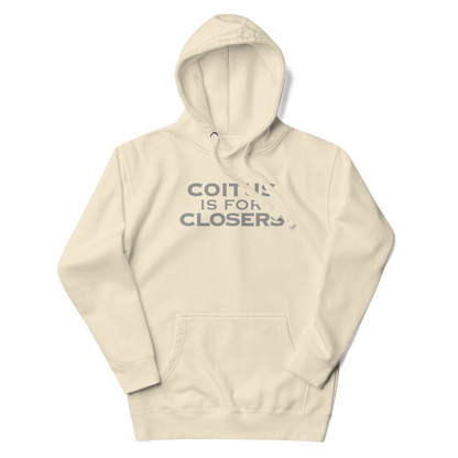 "Coitus Is For Closers" printed on a bone unisex hoodie laying on a flat surface with the hood up