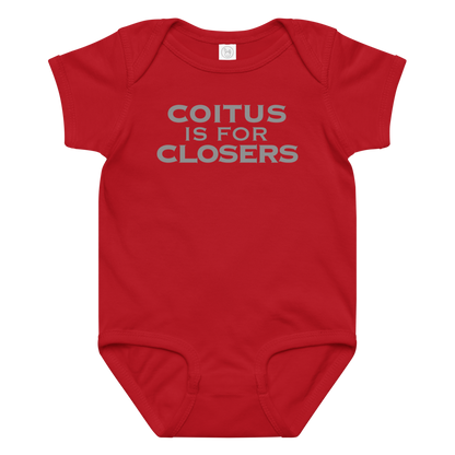 "Coitus Is For Closers" printed on a red baby jersey bodysuit laying on a flat surface amongst other clothes