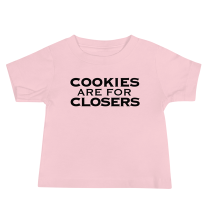 "Cookies Are For Closers" printed on a pink baby jersey short sleeve tee laying on a flat surface